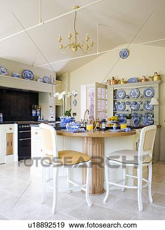Stock Photo - Cream chairs and wood breakfast bar in cream country kitchen. Fotosearch
