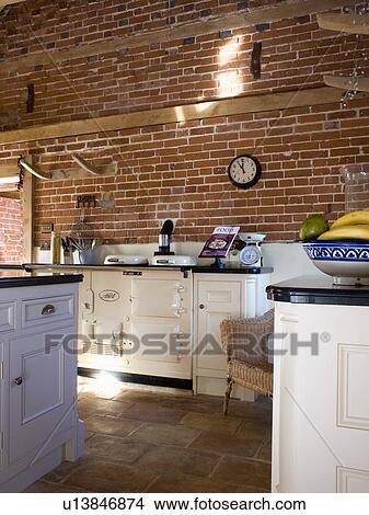 Picture - Cream double Aga oven in barn conversion kitchen with exposed brick wall. Fotosearch