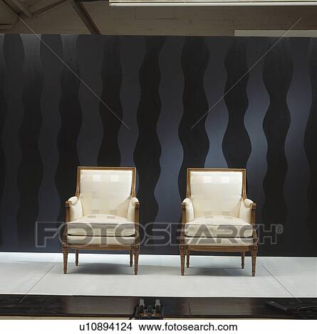 Picture - Cream silk upholstered armchairs against black background. Fotosearch