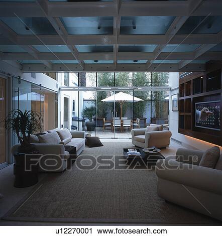 Stock Image - Cream sofas in large openplan modern white living room with cream carpet. Fotosearch