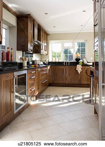 Stock Photography - Cream tiled floor in country kitchen with dark wood fitted units. Fotosearch