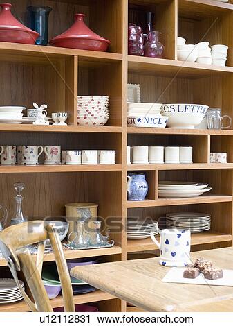 Stock Image - Crockery stored on wooden shelving in kitchen dining room. Fotosearch
