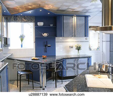 Dark blue fitted units in modern kitchen with triangular breakfast bar View Large Photo Image Stock Photo - Dark blue fitted units in modern kitchen with triangular breakfast bar. Fotosearch