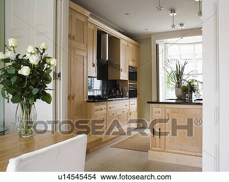 Picture - Dining room with double doors open to modern kitchen with pale wood units . Fotosearch