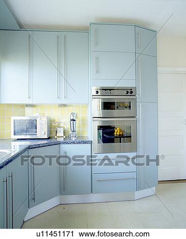 Stock Image - Double oven in modern kitchen with pastel blue fitted units. Fotosearch