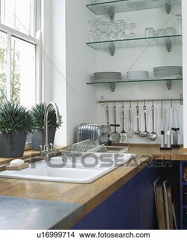 Picture - Double white sink with glass shelves above steel utensils on metal storage rack . Fotosearch