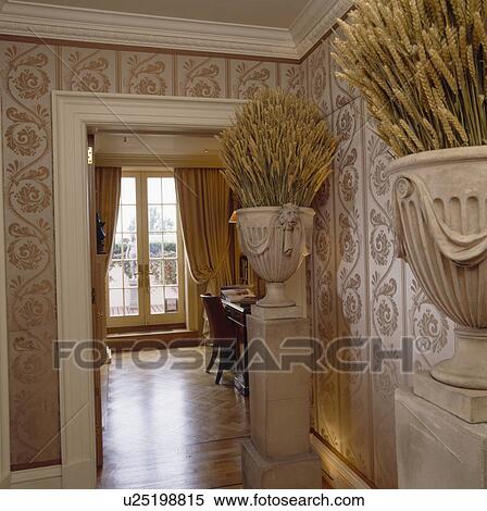 Stock Photography - Dried corn in stone urns on plinths in hall with silk wallpaper and oprn door to dining room. Fotosearch
