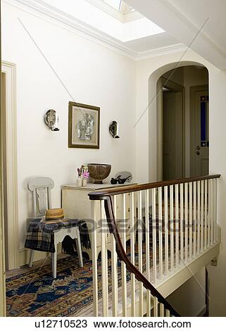 Stock Image - Early 19th-century Swedish chair and cream chest of drawers on Georgian landing. Fotosearch