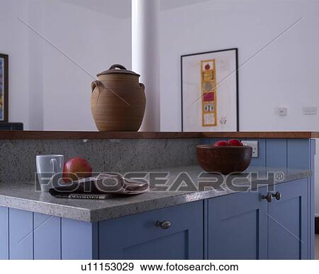 Stock Photo - Earthenware jar on shelf above blue kitchen unit with granite worktop. Fotosearch