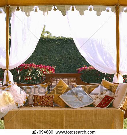 Embroidered cushions on old cane and wood settle in traditional Rajastani tent with white drapes View Large Photo Image Stock Image - Embroidered cushions on old cane and wood settle in traditional Rajastani tent with white drapes. Fotosearch