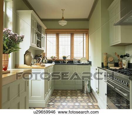 Encaustic tiled floor in country kitchen with fitted units painted in pastel green Farrow+Ball paint View Large Photo Image Stock Photograph - Encaustic tiled floor in country kitchen with fitted units painted in pastel green Farrow+Ball paint. Fotosearch
