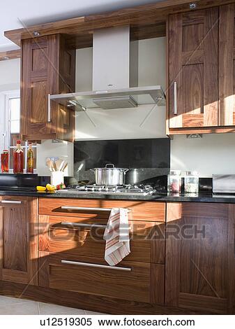 Stock Photography - Extractor above hob in fitted cherrywood unit in modern kitchen. Fotosearch