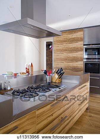 Stock Photograph - Extractor above hob in fitted unit with stainless steel worktop and veneered cupboard doors. Fotosearch