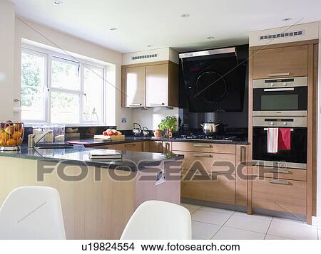 Picture - Eye-level double oven in pale wood fitted unit in modern kitchen. Fotosearch