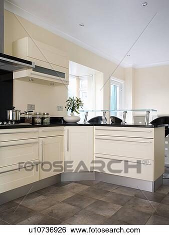 Stock Photograph - Fitted cream units in modern whtie country kitchen. Fotosearch