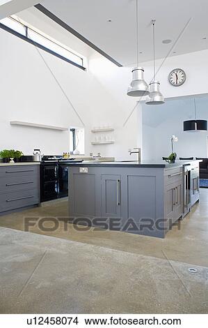 Picture - Fitted grey island unit in modern white ktichen with concrete flooring. Fotosearch