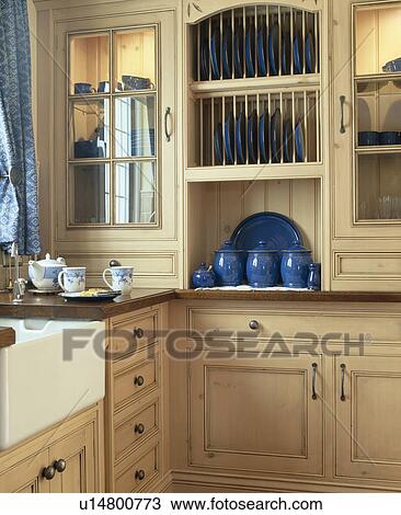 Stock Image - Fitted plate rack in small kitchen with pale wood units. Fotosearch