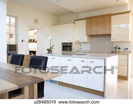 Stock Photo - Fitted white cupboards in long island unit in modern kitchen dining room. Fotosearch