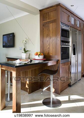 Fitted wood table in modern kitchen with dark wood fitted units View Large Photo Image Stock Photo - Fitted wood table in modern kitchen with dark wood fitted units. Fotosearch