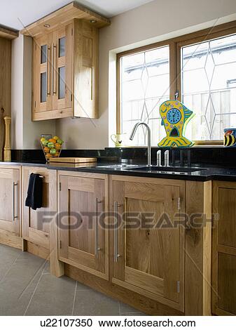Stock Image - Fitted wood units in modern beige kitchen. Fotosearch