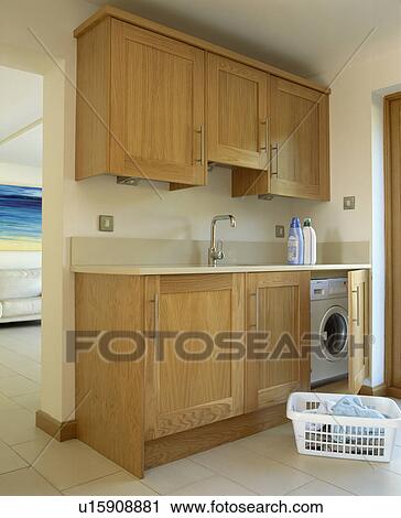 Stock Image - Fitted wooden cupboards concealing washing machine in utilily room. Fotosearch
