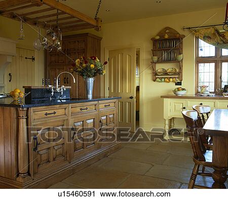 Stock Image - Flagstoned floor in large country kitchen with chestnut wood island unit. Fotosearch