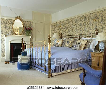Floral wallpaper and brass bed with blue bedcover in country bedroom View Large Photo Image Picture - Floral wallpaper and brass bed with blue bedcover in country bedroom. Fotosearch