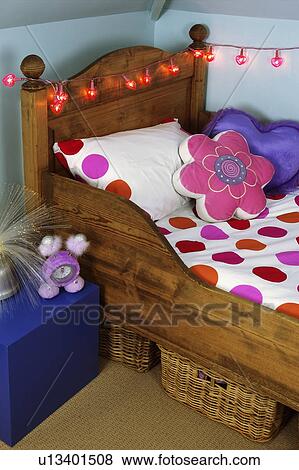 Flower-shaped cushion and pink and red spotted bedlinen on wooden bed with red fairy lights View Large Photo Image Stock Photo - Flower-shaped cushion and pink and red spotted bedlinen on wooden bed with red fairy lights. Fotosearch