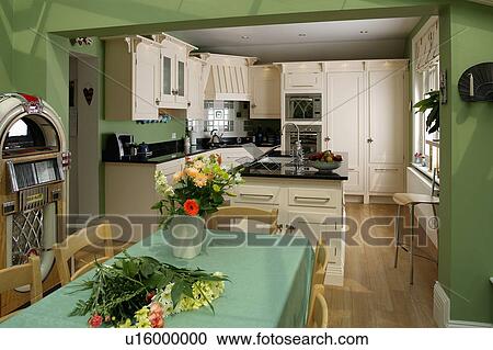 Stock Image - Flowers and green cloth on table in green kitchen dining room extension. Fotosearch
