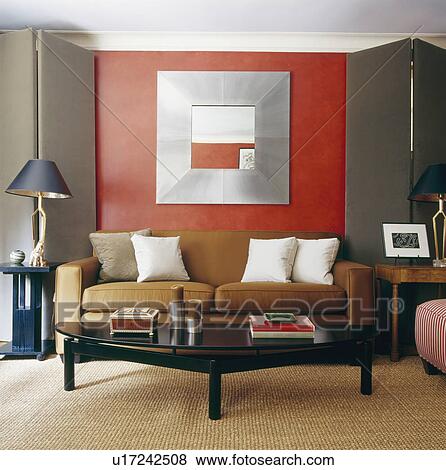 Folding grey fabric screens on either side of sofa below metal framed mirror in modern red living room with sisal carpet View Large Photo Image Stock Photo - Folding grey fabric screens on either side of sofa below metal framed mirror in modern red living room with sisal carpet. Fotosearch