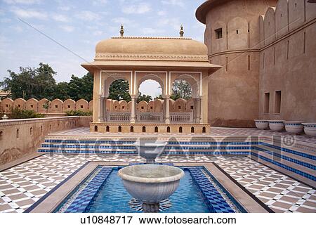 Stock Photo - Fountain and blue tiled pool in courtyard of sandstone fort at the Rajvilas Hotel near Jaipur. Fotosearch
