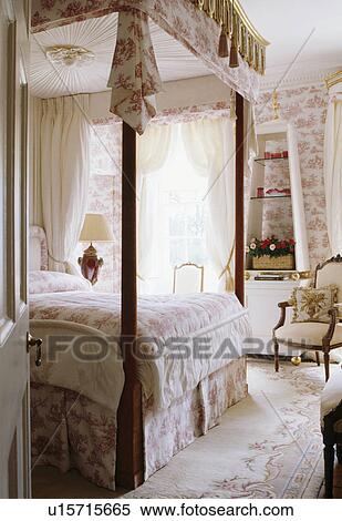 Stock Photography - Four-poster bed in coungtry bedroom with Toile-de-Jouy wallpaper. Fotosearch