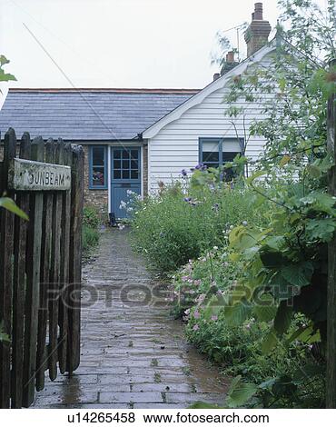 Stock Photo - Gate open to path through front garden to small white ship-lap house. Fotosearch