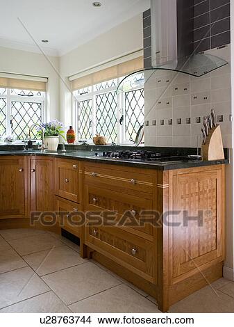 Glass and chrome extractor above hob in worktop in fitted wood kitchen unit View Large Photo Image Picture - Glass and chrome extractor above hob in worktop in fitted wood kitchen unit. Fotosearch