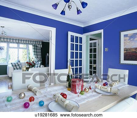 Glass baubles and white crackers on table in blue dining room with double doorway to living room View Large Photo Image Stock Photography - Glass baubles and white crackers on table in blue dining room with double doorway to living room. Fotosearch