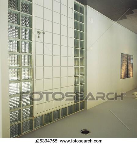 Stock Photography - Glass bricks on either side of front door in modern white hall. Fotosearch