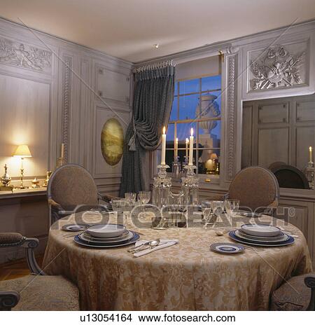 Glass candelabra on table with silk cloth set for dinner in pale grey panelled dining room with ornate plasterwork View Large Photo Image Picture - Glass candelabra on table with silk cloth set for dinner in pale grey panelled dining room with ornate plasterwork. Fotosearch