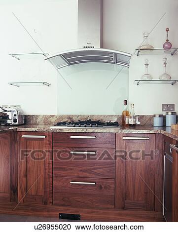 Glass shelves on either side of extractor in modern kitchen with dark wood fitted cupboards View Large Photo Image Stock Image - Glass shelves on either side of extractor in modern kitchen with dark wood fitted cupboards. Fotosearch