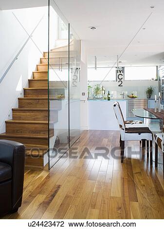 Glass wall dividing wooden staircase from modern white basement kitchen with wooden flooring View Large Photo Image Stock Image - Glass wall dividing wooden staircase from modern white basement kitchen with wooden flooring. Fotosearch