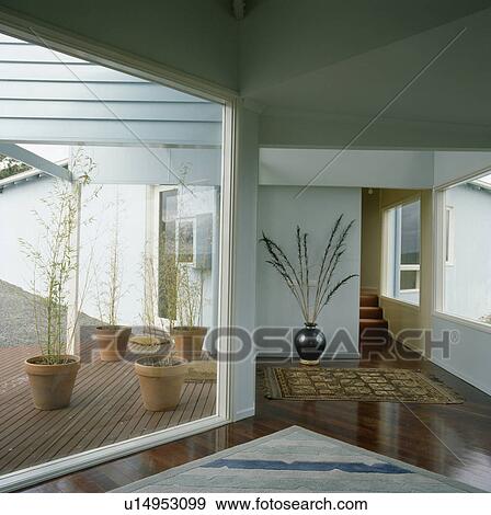 Glass wall with view of courtyard in modern white hall View Large Photo Image Stock Photo - Glass wall with view of courtyard in modern white hall. Fotosearch