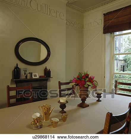 Picture - Gold ceramic coffee-pot and cups on table in dining room with large paint-effect letter border. Fotosearch