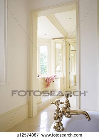 Stock Photo - Gold taps on bath in country bathroom with view of landing through open door. Fotosearch