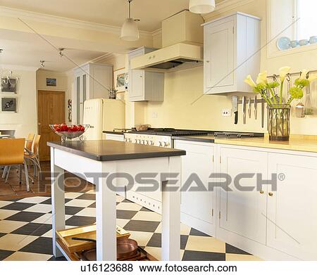 Granite-topped work-table in pale yellow country kitchen with white fitted units View Large Photo Image Stock Photo - Granite-topped work-table in pale yellow country kitchen with white fitted units. Fotosearch