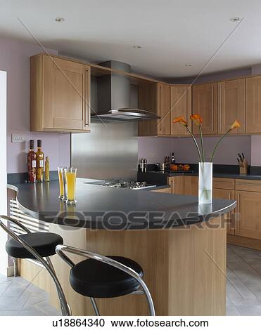 Stock Image - Granite worktop on curved peninsular unit in modern mauve kitchen with pale wood units. Fotosearch