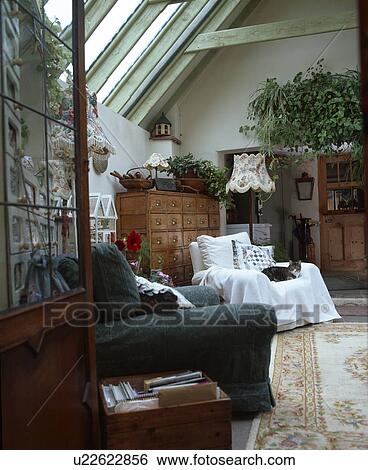 Stock Photograph - Green sofa and amrchair with white cotton throw in attic living room extension. Fotosearch