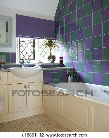 Stock Image - Green+purple tiled bathroom with purple blind on window. Fotosearch