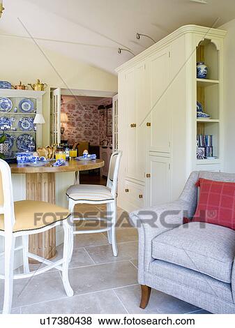 Stock Photo - Grey armchair beside breakfast bar in cream country kitchen. Fotosearch