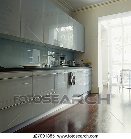 Stock Photography - Grey lacquered units in modern kitchen with polished wooden floor. Fotosearch