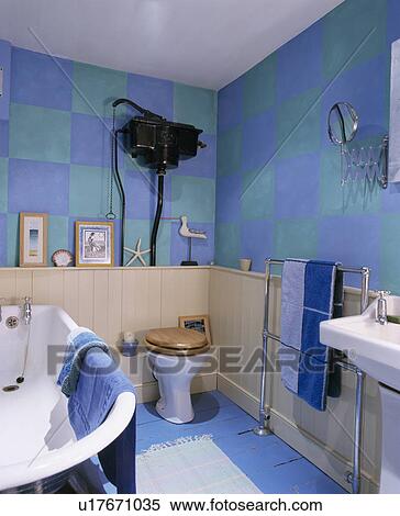 Stock Photography - Hand-painted blue+green checked walls in family bathroom with cream tongue+groove panelling. Fotosearch