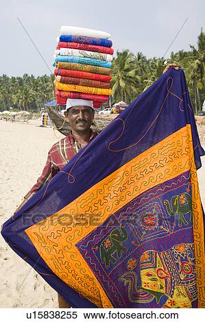 Stock Photography - Hawker on Kovalam Beach carrying tablecloths on his head, Kovalam, Kerala, India. Fotosearch